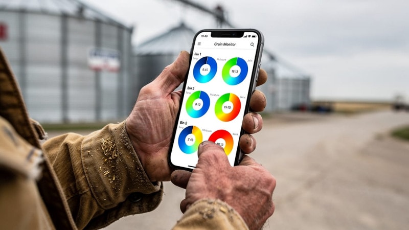 Farmer checking grain bin monitoring app on smartphone