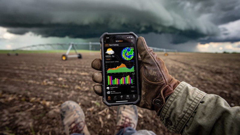 Farmer checking weather station data on smartphone in field